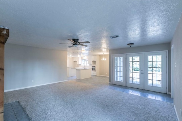 unfurnished living room with french doors, a textured ceiling, light colored carpet, and ceiling fan