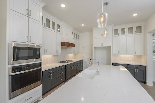 kitchen with white cabinetry, stainless steel appliances, sink, and custom exhaust hood