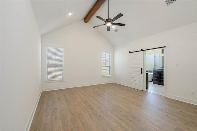 empty room featuring high vaulted ceiling, beamed ceiling, ceiling fan, a barn door, and light hardwood / wood-style floors