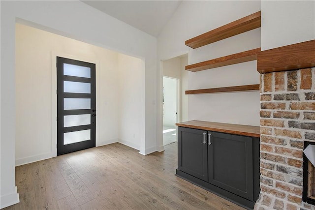 entrance foyer with lofted ceiling, a fireplace, and light hardwood / wood-style flooring