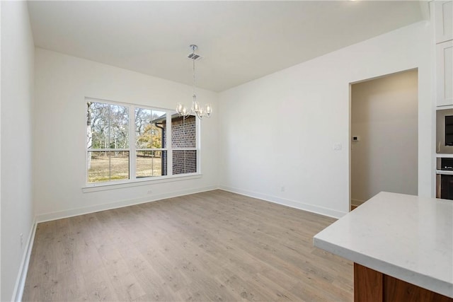 unfurnished dining area with a chandelier and light hardwood / wood-style floors