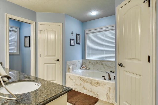 2703 Wood Ct, Bryan, TX 77808 - bathroom with vanity, a garden tub, and a textured ceiling
