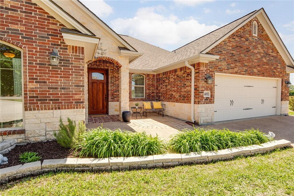 4002 Wild Creek Ct, College Station, TX 77845 - view of front of home with driveway, a garage, brick siding, and roof with shingles