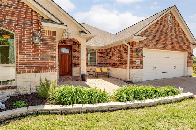 view of front facade with driveway, roof with shingles, stone siding, a garage, and brick siding