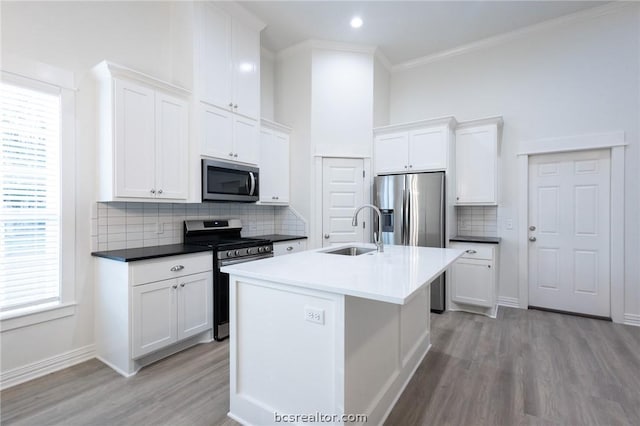 kitchen with sink, white cabinetry, stainless steel appliances, and light hardwood / wood-style flooring