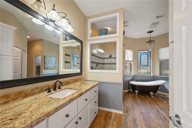 full bath with visible vents, wainscoting, wood finished floors, a tile shower, and vanity