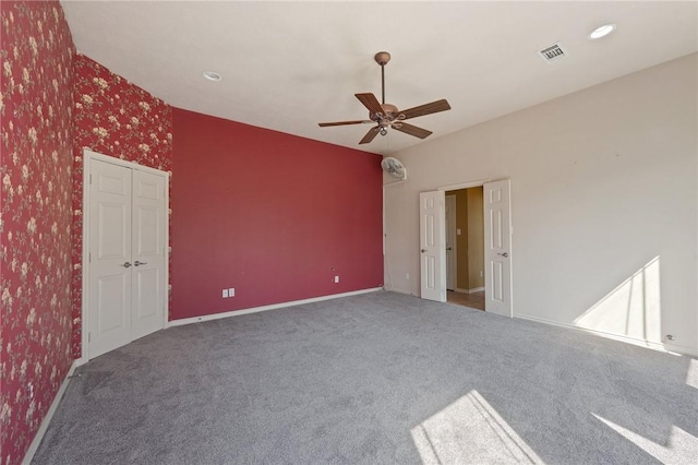 carpeted spare room featuring wallpapered walls, baseboards, visible vents, and a ceiling fan