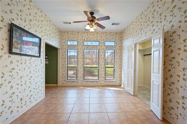 empty room featuring light tile patterned floors, visible vents, baseboards, and wallpapered walls