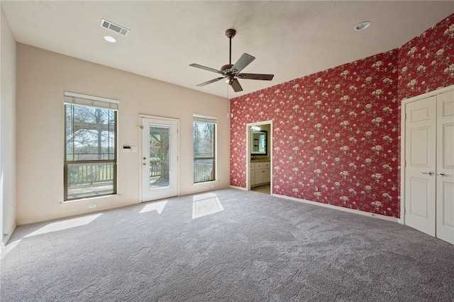 carpeted empty room with wallpapered walls, baseboards, visible vents, and ceiling fan