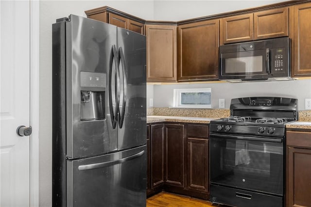 2099 Positano Loop, Bryan, TX 77808 - kitchen featuring black appliances, wood finished floors, and light stone counters