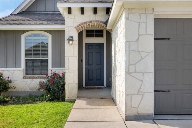 2099 Positano Loop, Bryan, TX 77808 - view of exterior entry with board and batten siding, stone siding, and a shingled roof