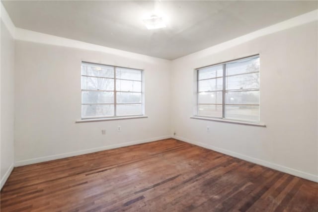 empty room featuring dark wood-type flooring and a healthy amount of sunlight