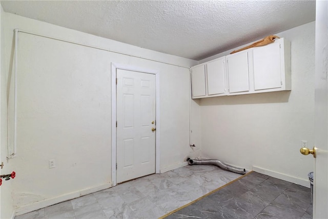 laundry area featuring cabinets and a textured ceiling