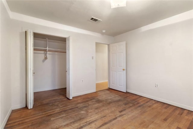 unfurnished bedroom with dark hardwood / wood-style flooring and a closet