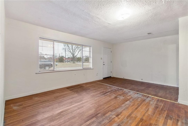 unfurnished room with hardwood / wood-style floors and a textured ceiling