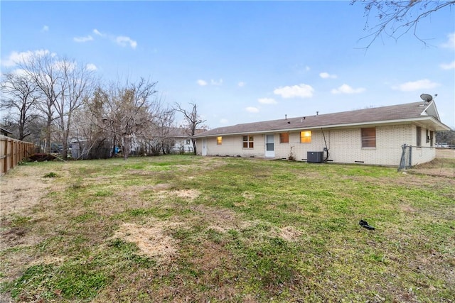 rear view of house with central AC unit and a lawn