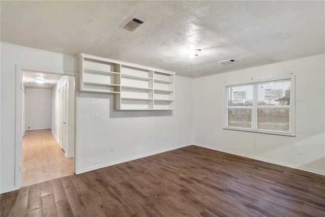 spare room featuring wood-type flooring and a textured ceiling