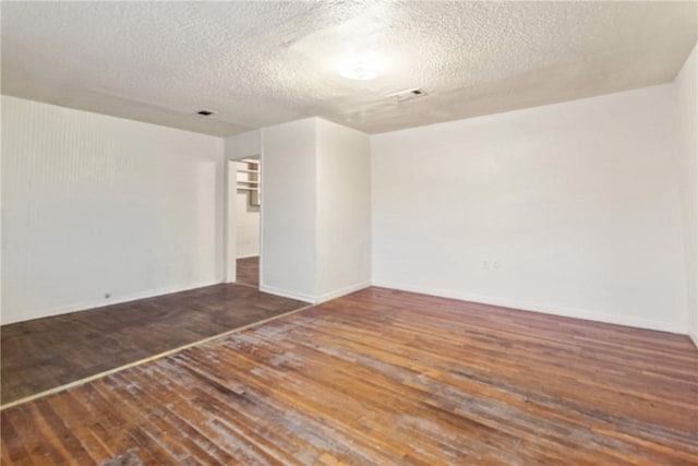 empty room featuring dark hardwood / wood-style floors and a textured ceiling