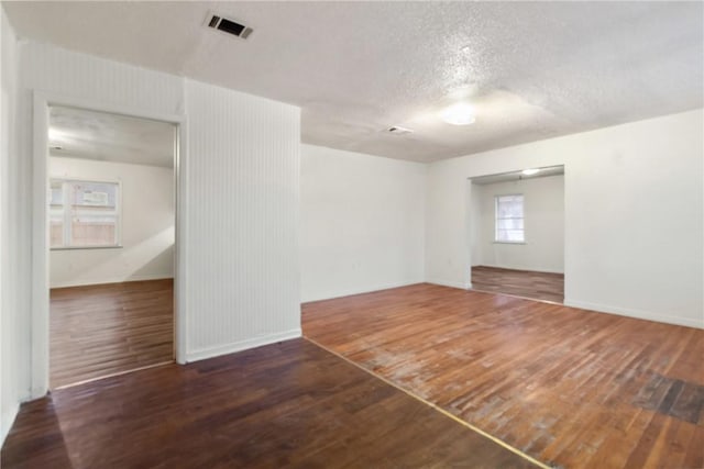 empty room with dark wood-type flooring and a textured ceiling