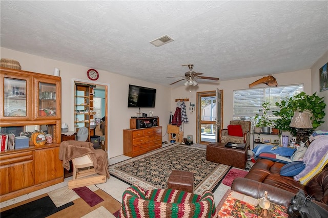 living room with ceiling fan and a textured ceiling