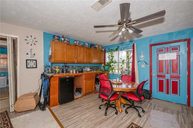 dining area with ceiling fan, light hardwood / wood-style floors, and a textured ceiling