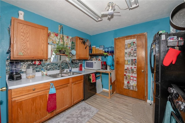 kitchen featuring sink, backsplash, light hardwood / wood-style floors, a textured ceiling, and black appliances