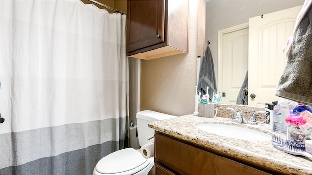 bathroom featuring toilet, a textured wall, and vanity