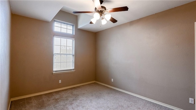 carpeted spare room featuring a ceiling fan and baseboards