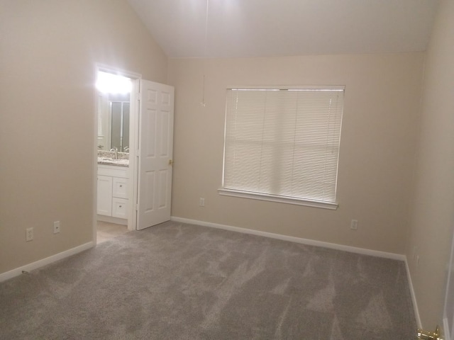 unfurnished bedroom featuring baseboards, vaulted ceiling, a sink, and light colored carpet