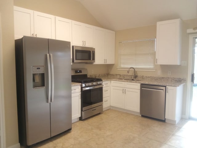 kitchen with appliances with stainless steel finishes, a sink, white cabinetry, and light stone countertops