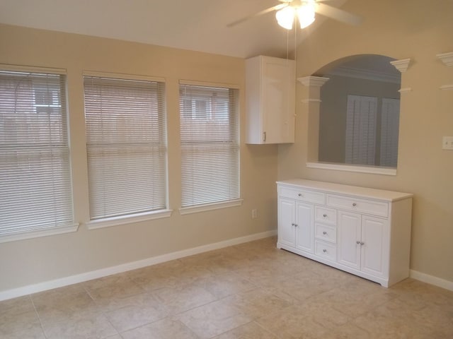 interior space with ornamental molding, ceiling fan, baseboards, and light tile patterned floors