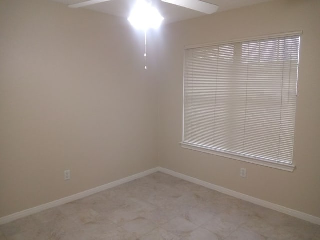 spare room with ceiling fan and baseboards