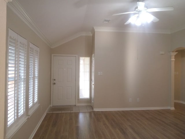 entrance foyer with ornamental molding, arched walkways, vaulted ceiling, and wood finished floors