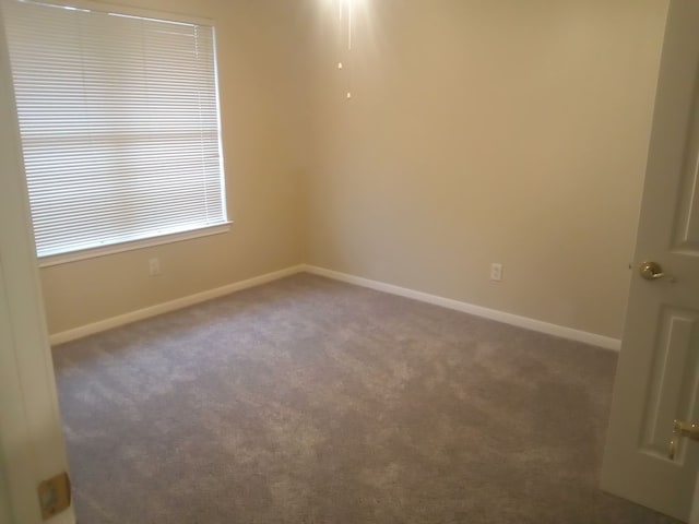 carpeted empty room featuring baseboards