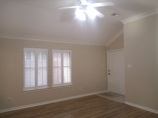 spare room with baseboards, visible vents, lofted ceiling, ornamental molding, and wood finished floors