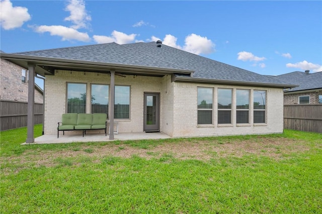 back of house with roof with shingles, brick siding, a fenced backyard, an outdoor hangout area, and a patio