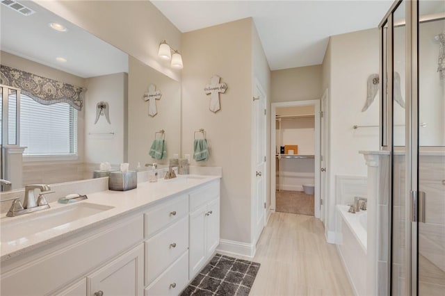 bathroom with double vanity, visible vents, a sink, and a bath