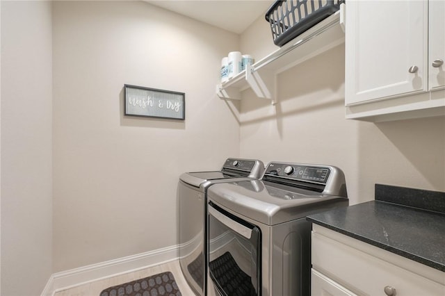 clothes washing area featuring baseboards, cabinet space, and independent washer and dryer