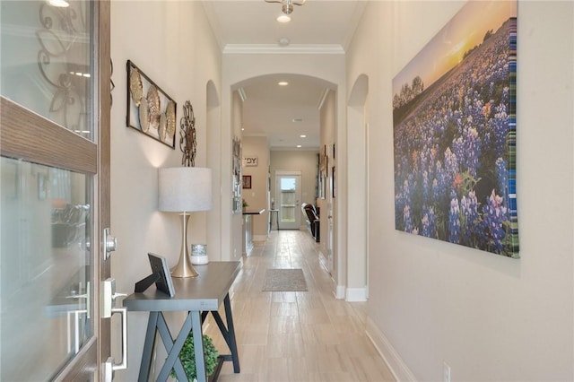 hall featuring arched walkways, baseboards, and ornamental molding