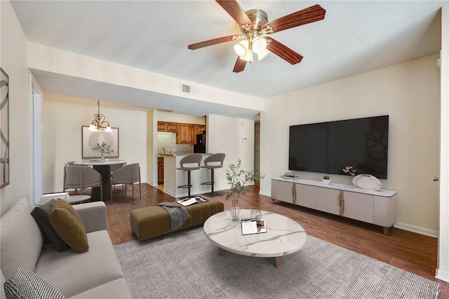 living area with light wood-type flooring, baseboards, visible vents, and ceiling fan with notable chandelier