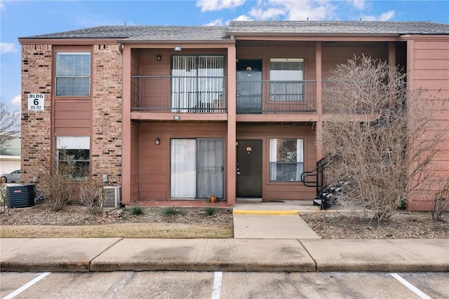 view of front of house with uncovered parking, brick siding, and cooling unit