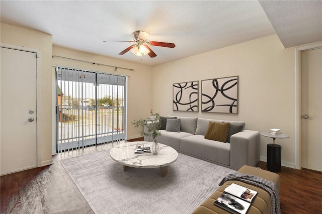 living room featuring a textured ceiling, wood finished floors, a ceiling fan, and baseboards