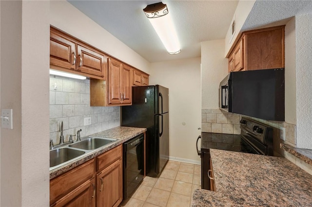 kitchen featuring brown cabinets, tasteful backsplash, light tile patterned flooring, a sink, and black appliances