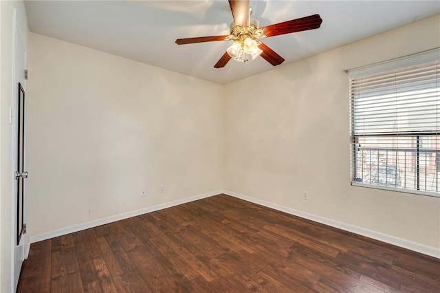 spare room featuring dark wood-style flooring, ceiling fan, and baseboards