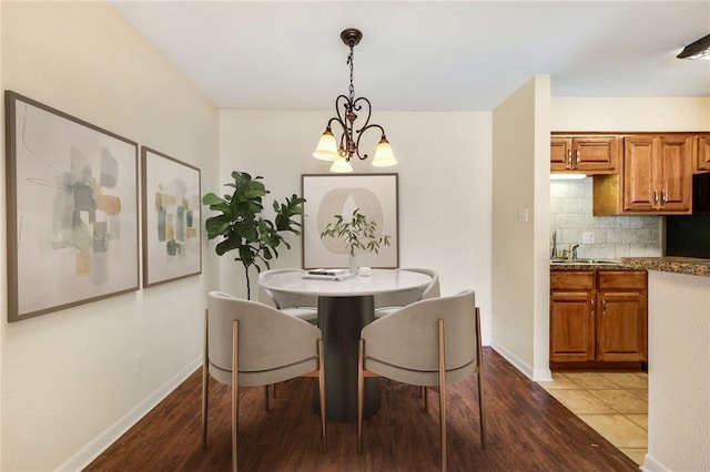 dining room with a chandelier, light wood finished floors, and baseboards