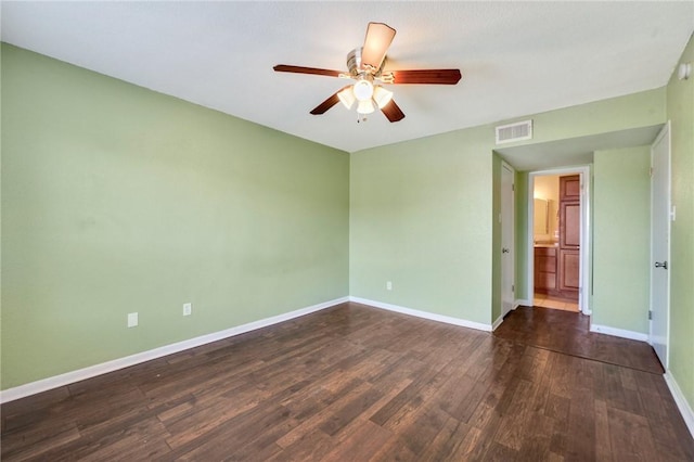 empty room featuring dark wood-type flooring, visible vents, ceiling fan, and baseboards