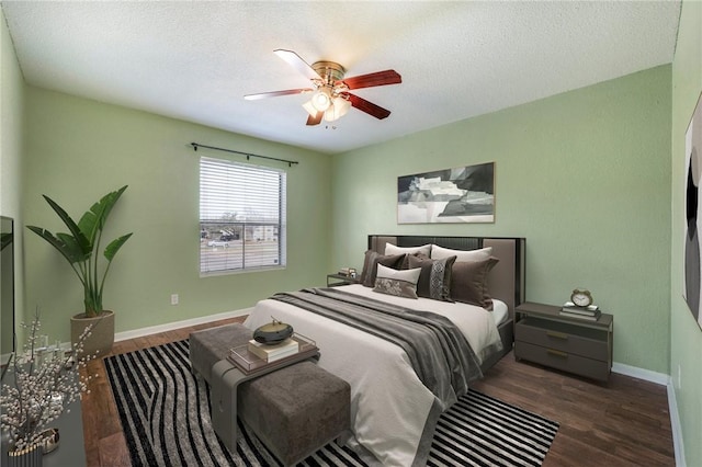 bedroom with a ceiling fan, a textured ceiling, baseboards, and wood finished floors