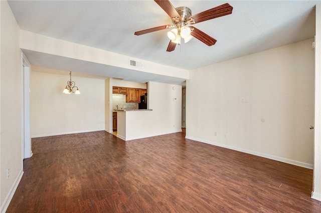 unfurnished living room with ceiling fan with notable chandelier, dark wood-style flooring, visible vents, and baseboards