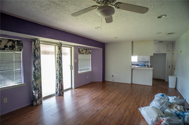 unfurnished living room featuring ceiling fan, wood-type flooring, and a textured ceiling