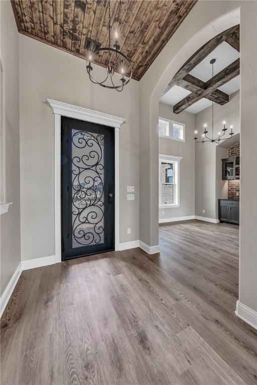 foyer entrance with a chandelier, beam ceiling, hardwood / wood-style flooring, and coffered ceiling